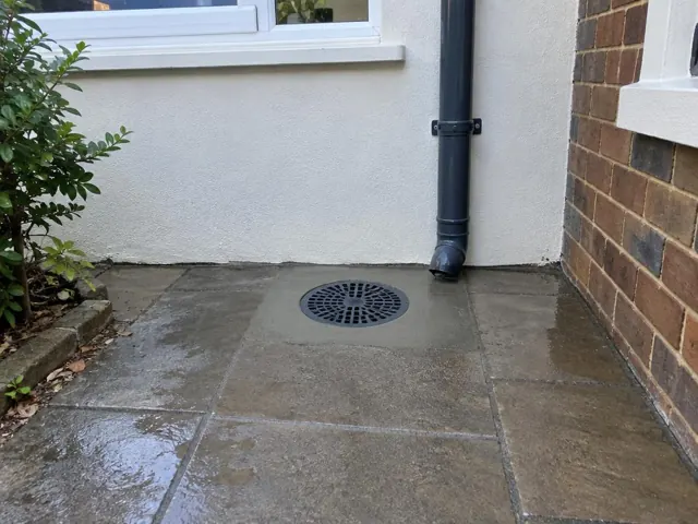 Outdoor drain grate in tiled paving beside brick and rendered walls in Leichhardt